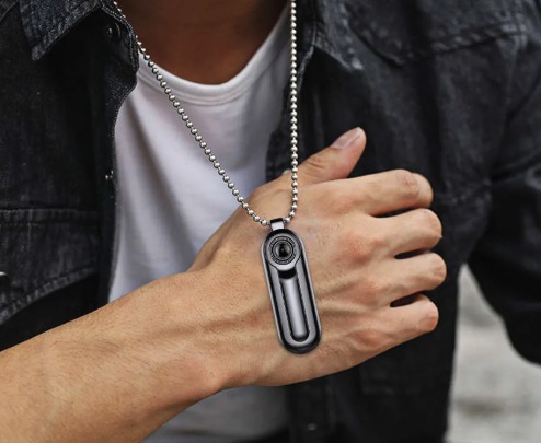 Mini videocamera nera a ciondolo indossata al collo di un uomo